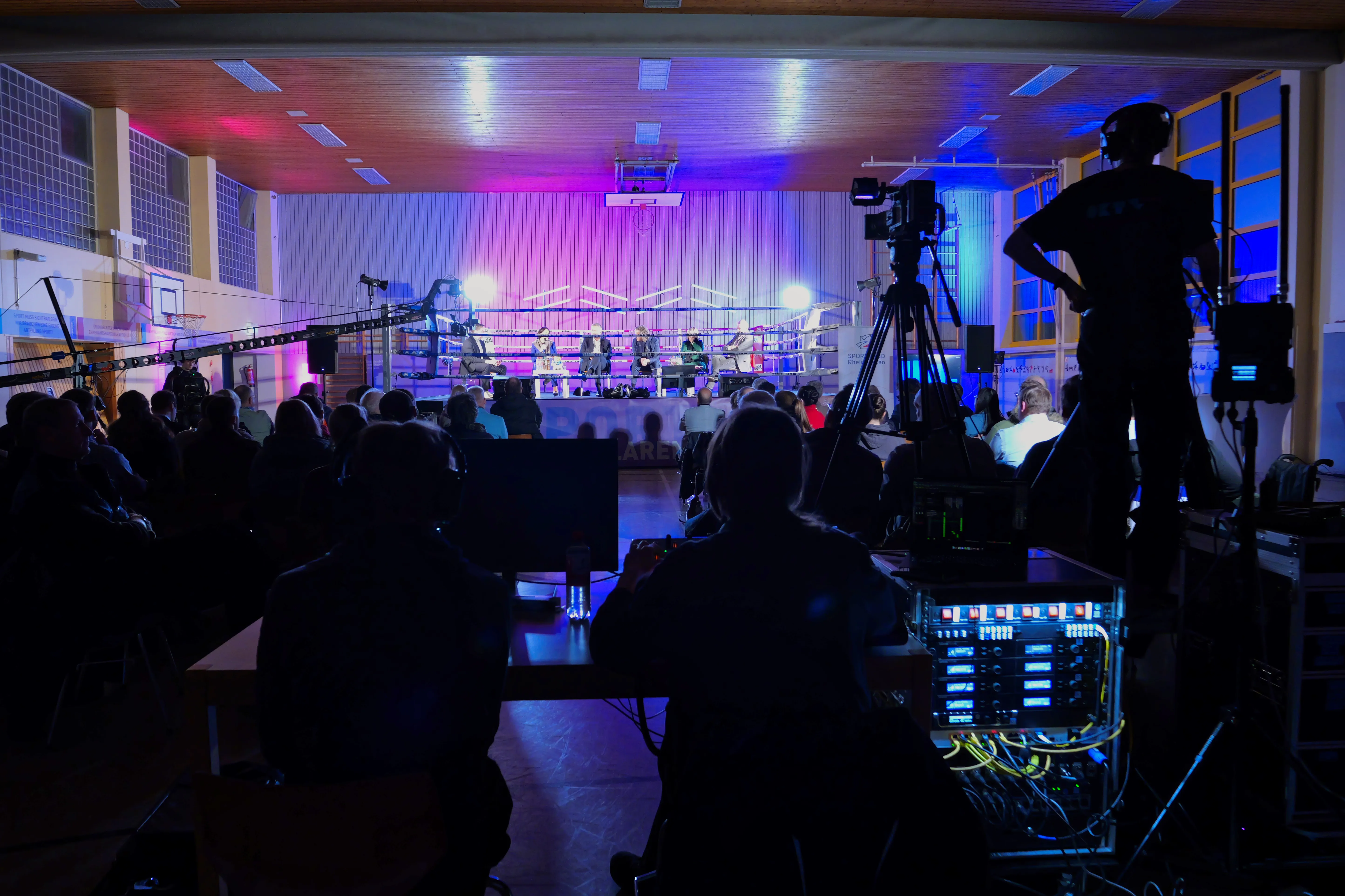 Sporthalle mit Boxring, Lichtinstallation und Publikum
